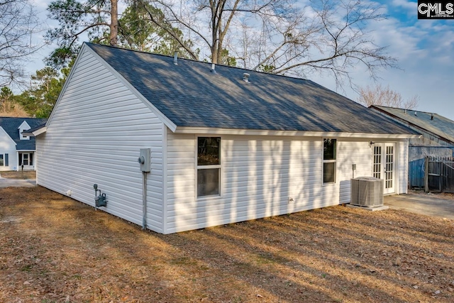 view of side of property featuring central AC and roof with shingles