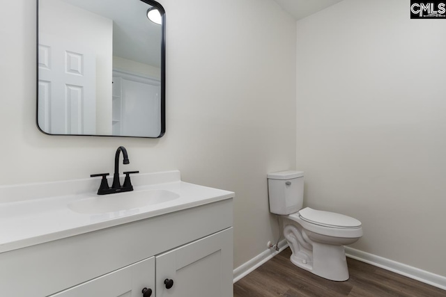 bathroom with toilet, baseboards, wood finished floors, and vanity