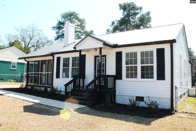 view of front of home featuring a sunroom, a chimney, metal roof, crawl space, and fence