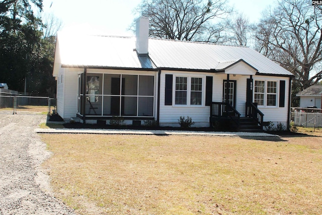 view of front of property with metal roof, a front lawn, fence, and a sunroom