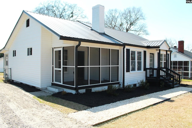 exterior space featuring a sunroom, metal roof, and a chimney