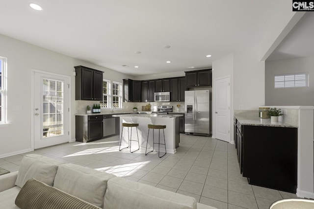 kitchen featuring appliances with stainless steel finishes, open floor plan, a breakfast bar area, and light tile patterned floors