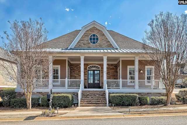 view of front facade featuring a shingled roof, a standing seam roof, covered porch, and metal roof