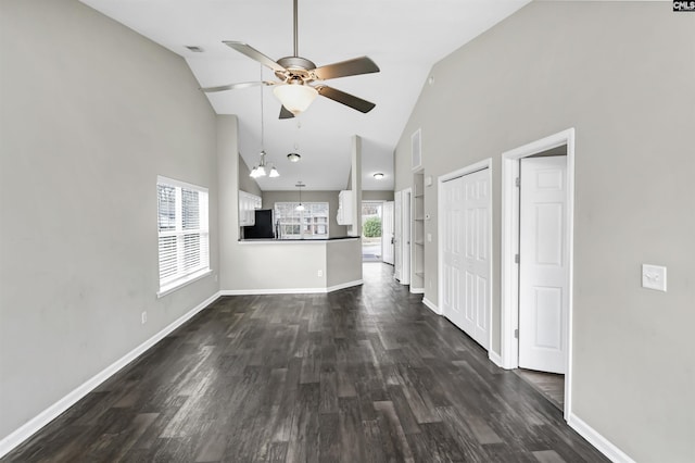 unfurnished living room with a wealth of natural light, visible vents, dark wood finished floors, and baseboards