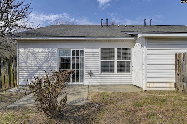 rear view of property featuring a patio, a shingled roof, and fence