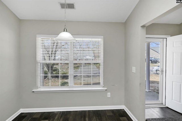 unfurnished dining area featuring visible vents, dark wood finished floors, and baseboards