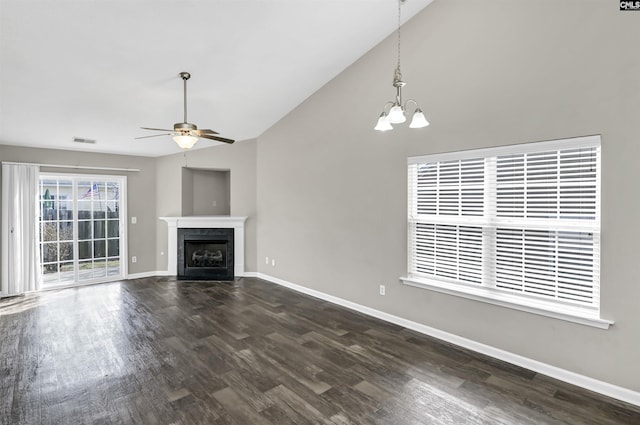 unfurnished living room featuring baseboards, a fireplace with flush hearth, dark wood-style flooring, vaulted ceiling, and ceiling fan with notable chandelier