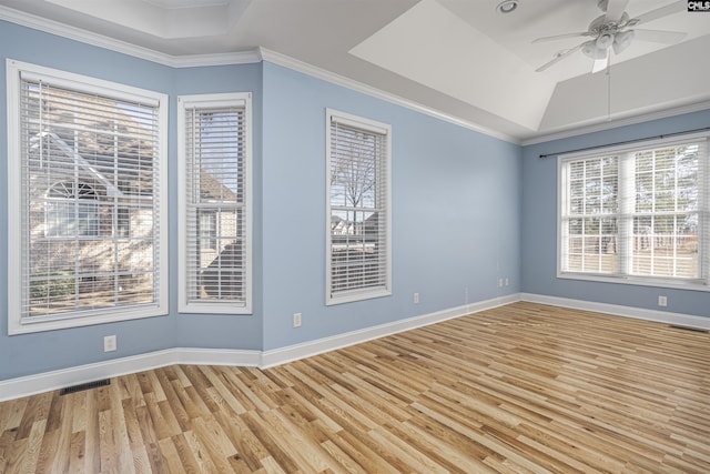 spare room with baseboards, light wood-type flooring, a raised ceiling, and crown molding