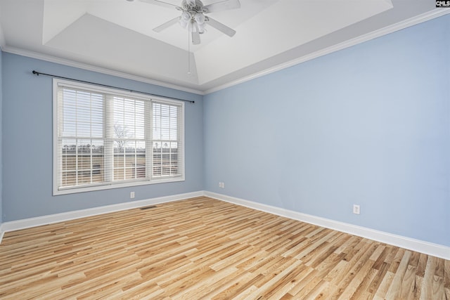 spare room featuring baseboards, a tray ceiling, and light wood-style floors