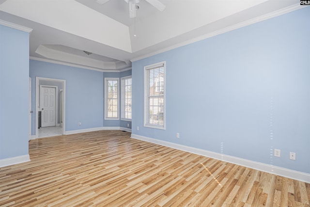 unfurnished room with a raised ceiling, crown molding, light wood-style flooring, and baseboards