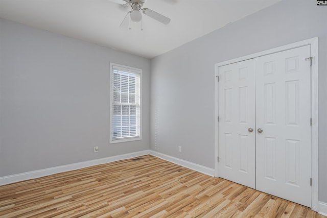 unfurnished bedroom with baseboards, ceiling fan, a closet, and light wood-style floors