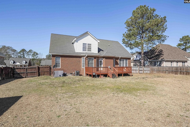 back of property featuring brick siding, a lawn, a fenced backyard, and a wooden deck