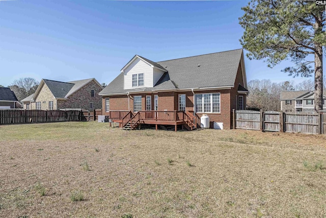 back of property featuring a deck, a yard, brick siding, and a fenced backyard