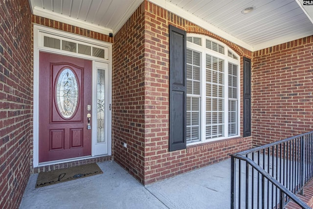 doorway to property with a porch and brick siding