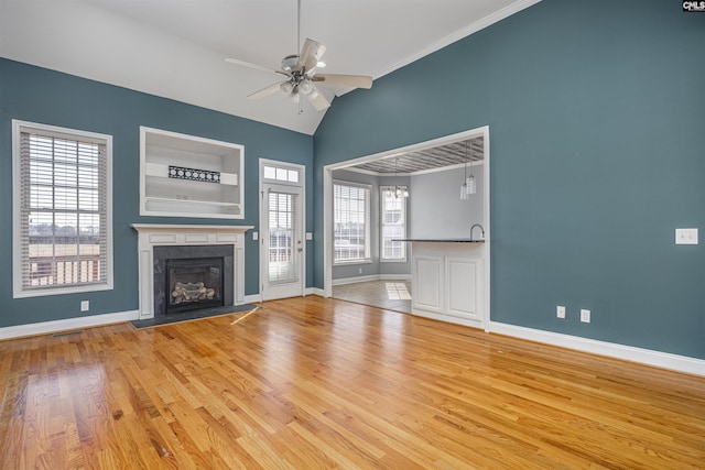 unfurnished living room with a fireplace, lofted ceiling, ceiling fan, wood finished floors, and baseboards