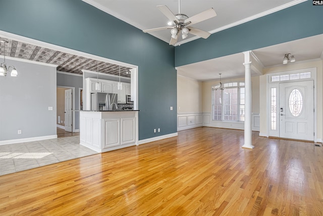 unfurnished living room with ornamental molding, ornate columns, and ceiling fan with notable chandelier