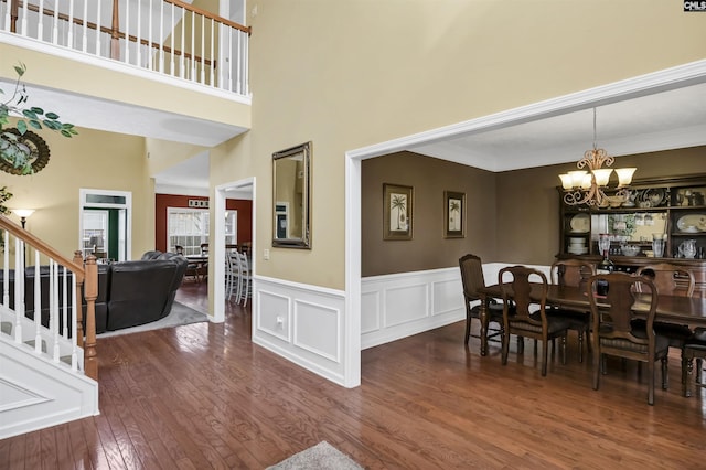 dining area featuring a wainscoted wall, stairway, ornamental molding, wood finished floors, and a notable chandelier