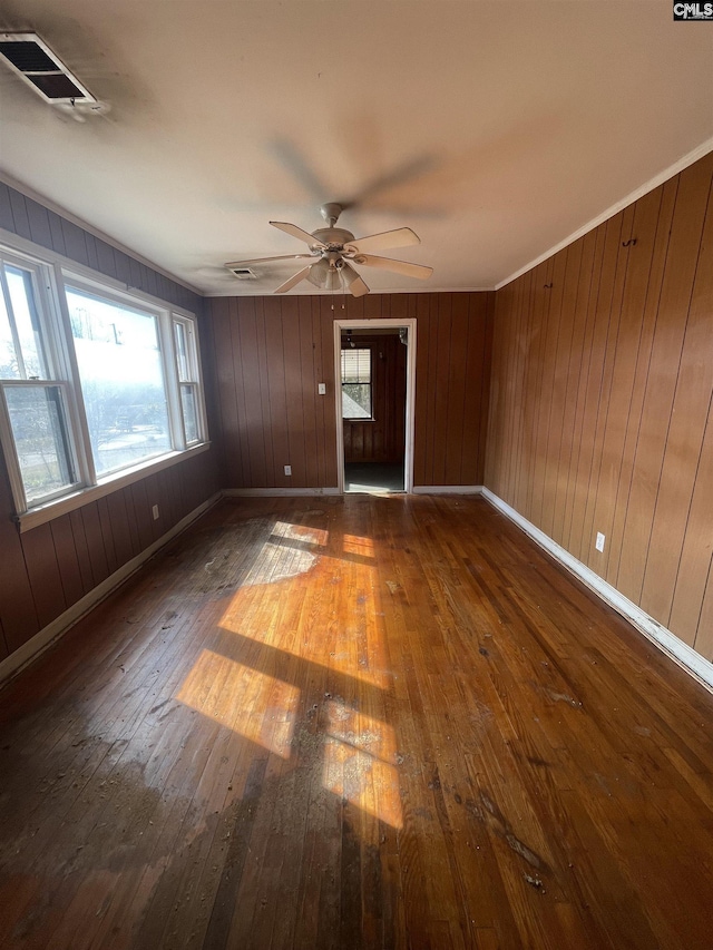 unfurnished room with a ceiling fan, baseboards, visible vents, and hardwood / wood-style floors