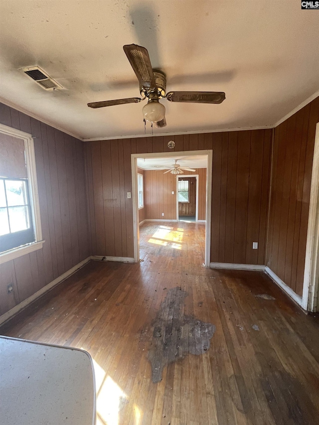 unfurnished room with a wealth of natural light, visible vents, crown molding, and hardwood / wood-style flooring