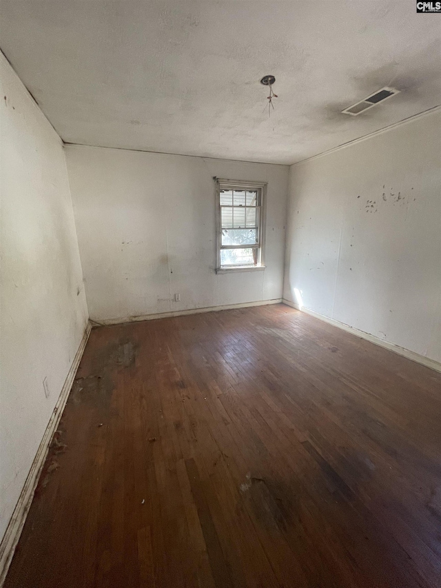 empty room featuring wood-type flooring, visible vents, and a textured ceiling