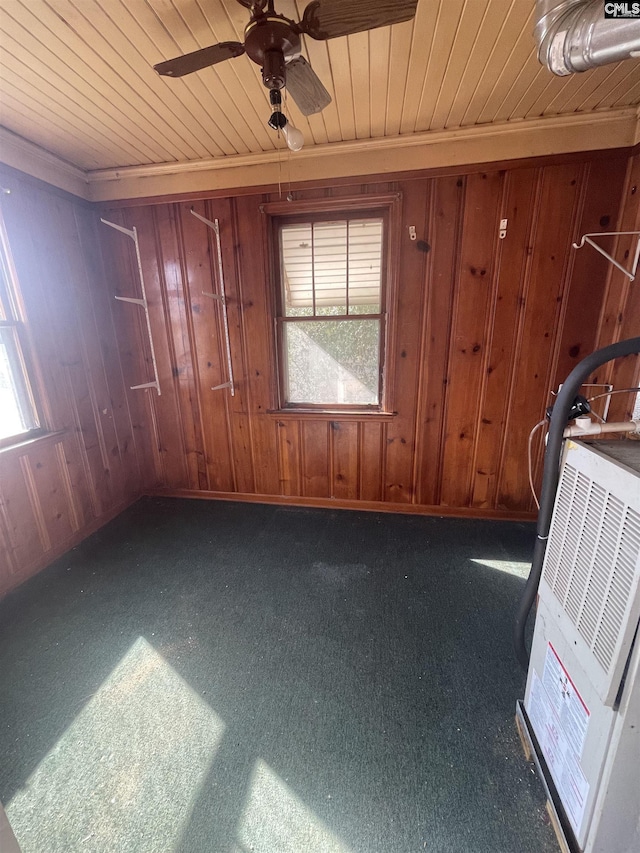 interior space featuring wood ceiling, wooden walls, ornamental molding, and ceiling fan