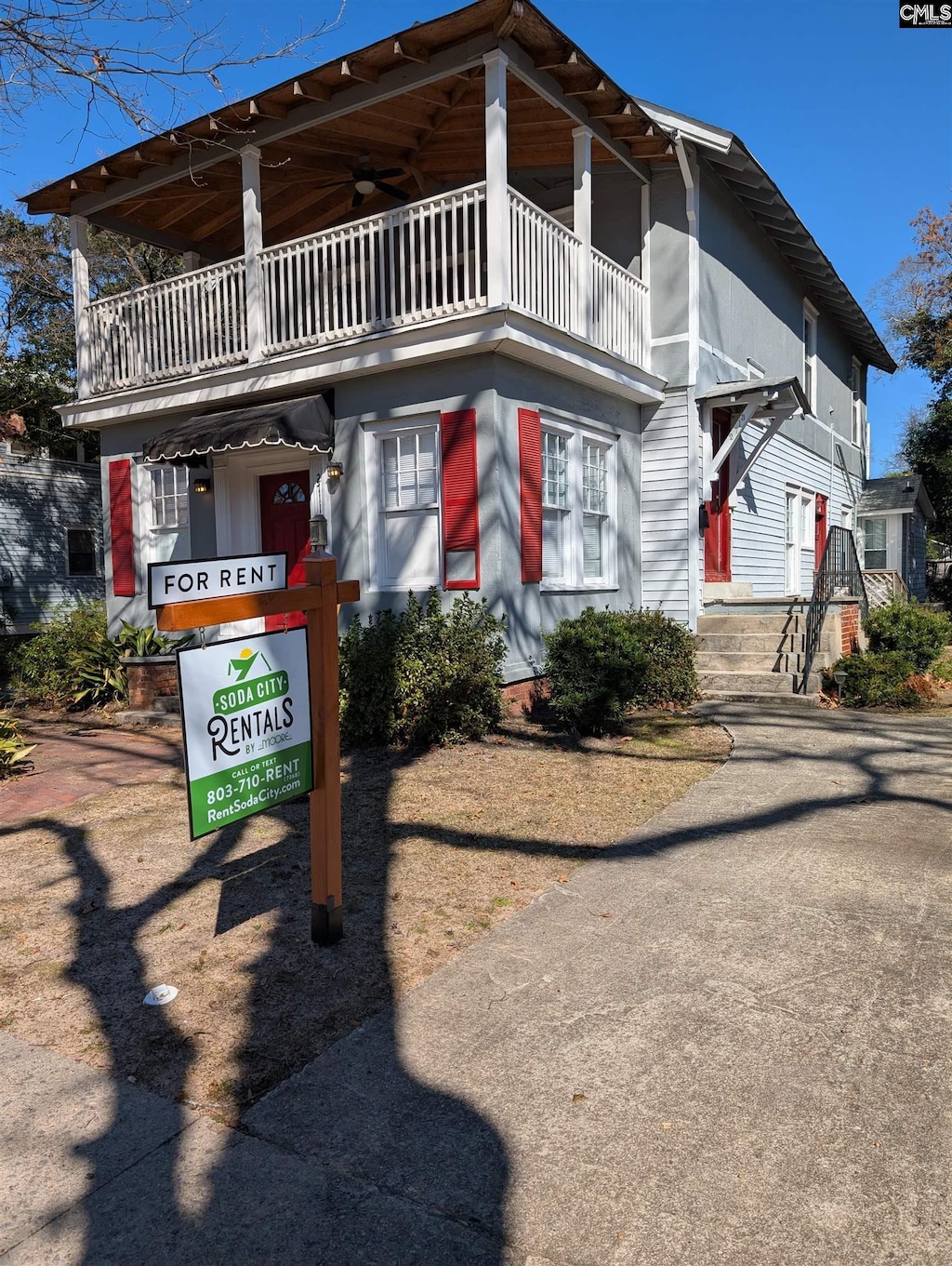 view of front of property with ceiling fan and a balcony