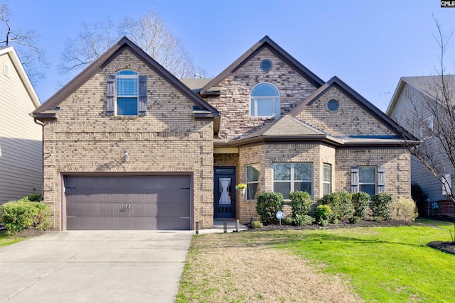 french country inspired facade with a garage, a front lawn, concrete driveway, and brick siding