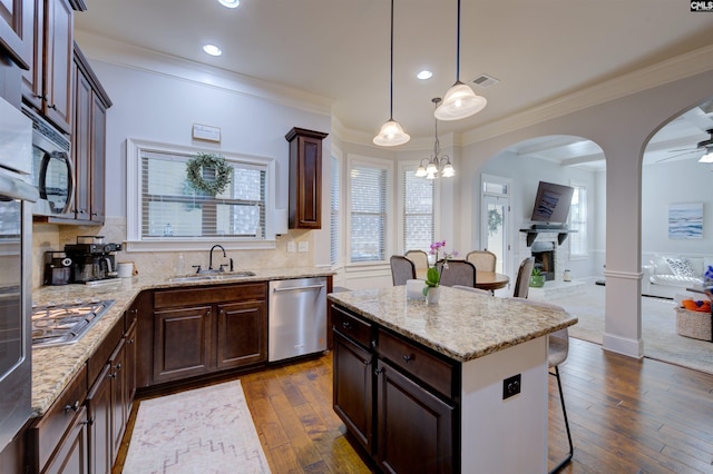 kitchen featuring visible vents, open floor plan, stainless steel appliances, a kitchen bar, and a sink