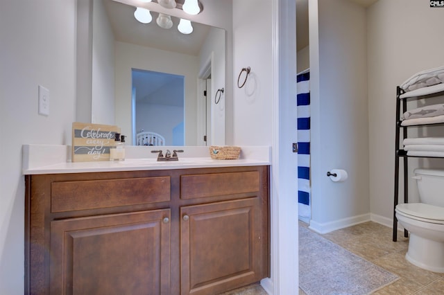 bathroom featuring baseboards, vanity, and toilet