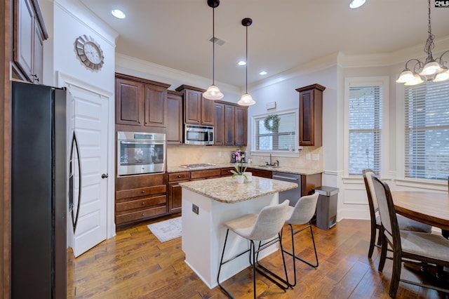 kitchen featuring stainless steel appliances, a sink, visible vents, a center island, and dark wood finished floors