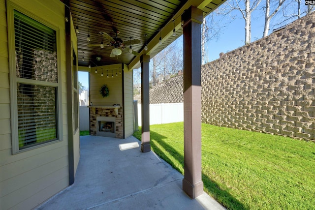 view of patio / terrace featuring ceiling fan, exterior fireplace, and fence