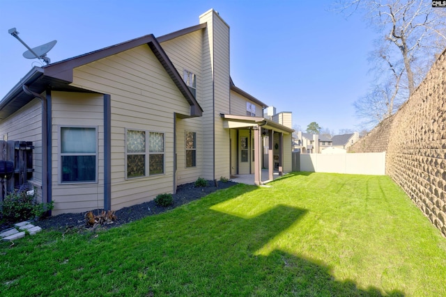 rear view of property with a patio area, a lawn, and fence