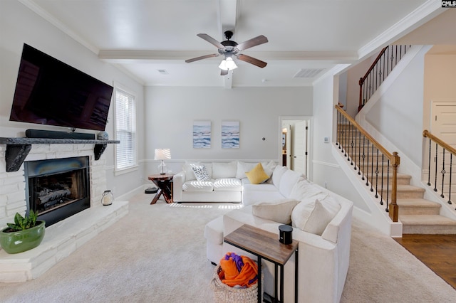 carpeted living room featuring stairs, a stone fireplace, visible vents, and crown molding