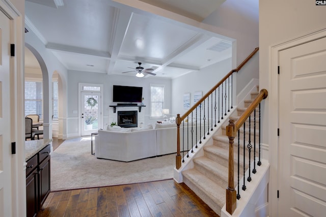 living area with dark wood finished floors, a fireplace, ceiling fan, coffered ceiling, and beamed ceiling