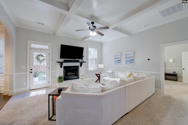 carpeted living area featuring coffered ceiling, visible vents, arched walkways, and beam ceiling