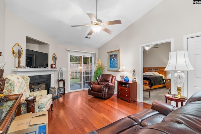 living room with visible vents, a high end fireplace, ceiling fan, vaulted ceiling, and wood finished floors