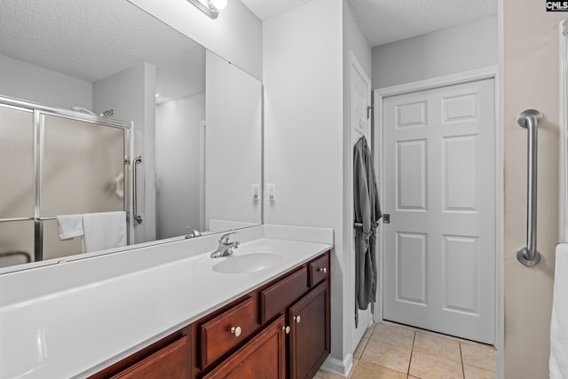 full bath with a stall shower, tile patterned flooring, a textured ceiling, and vanity