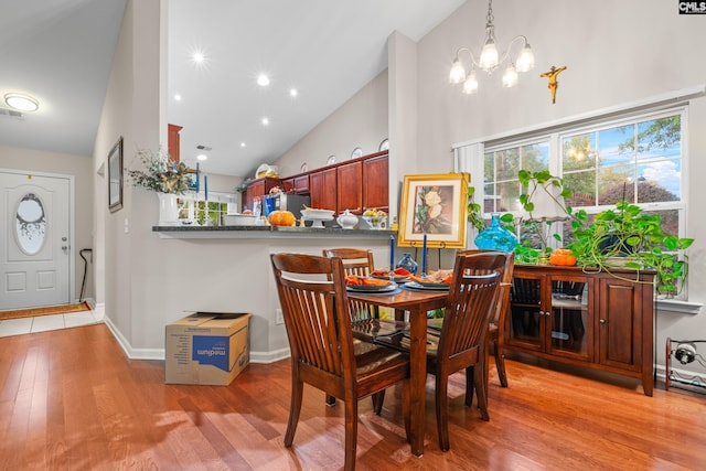 dining area with baseboards, wood finished floors, an inviting chandelier, high vaulted ceiling, and recessed lighting