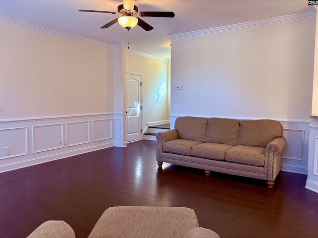 living room featuring wainscoting, ceiling fan, ornamental molding, wood finished floors, and a decorative wall