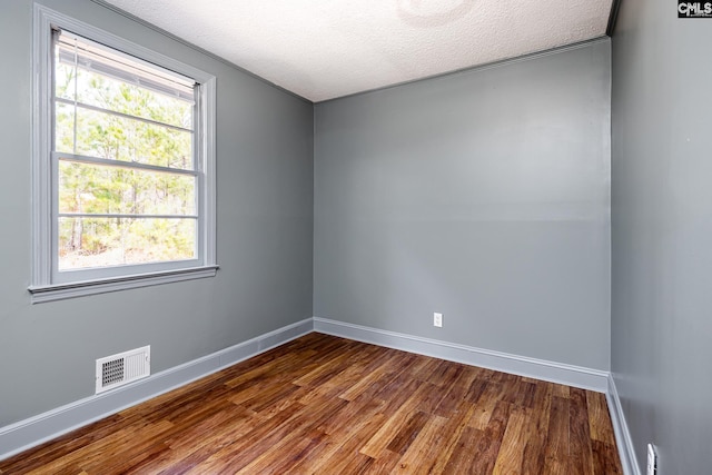 unfurnished room with baseboards, a textured ceiling, visible vents, and dark wood-style flooring