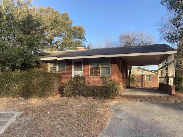 ranch-style home with an attached carport, brick siding, and driveway