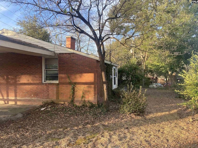 view of side of home with brick siding and a chimney