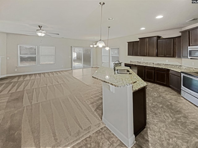 kitchen featuring a kitchen island with sink, a sink, dark brown cabinets, electric range oven, and stainless steel microwave