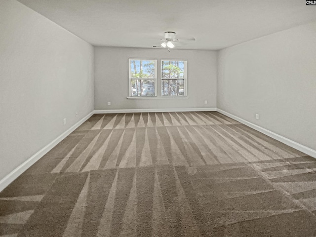 carpeted empty room featuring a ceiling fan and baseboards