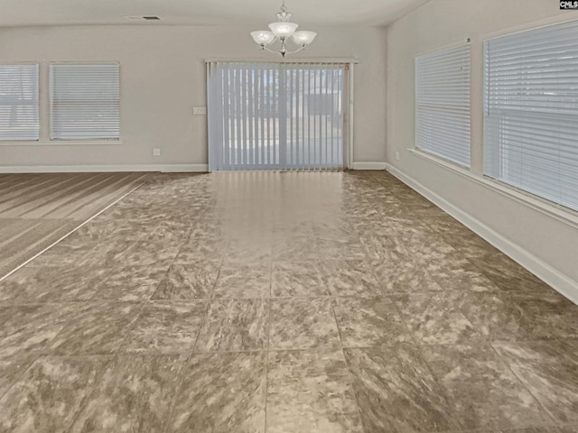 empty room with an inviting chandelier, baseboards, and visible vents