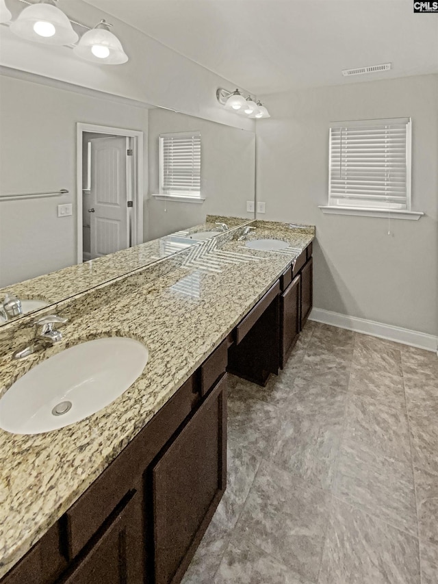 full bathroom featuring double vanity, visible vents, baseboards, and a sink