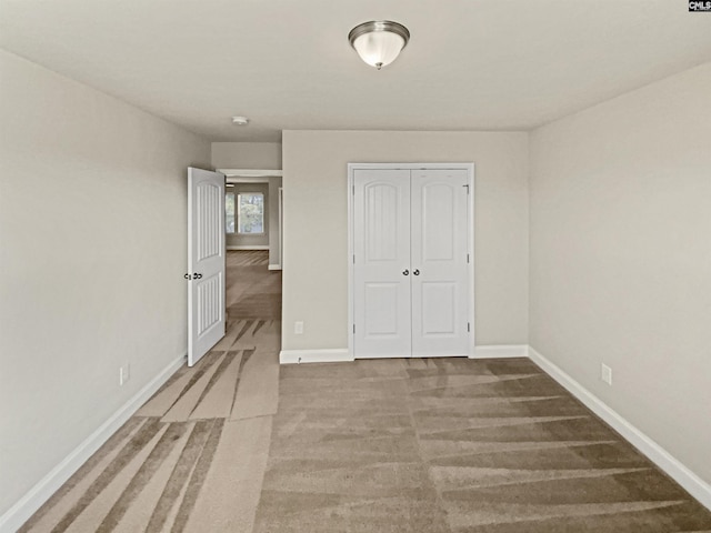 unfurnished bedroom featuring carpet, a closet, and baseboards