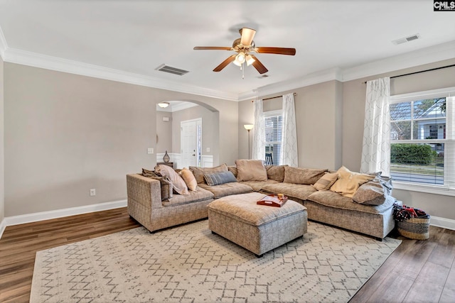 living area with arched walkways, visible vents, light wood-style flooring, and baseboards