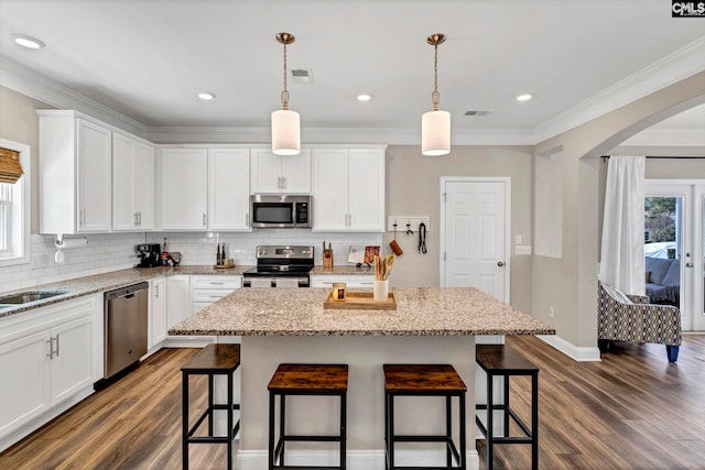 kitchen with arched walkways, stainless steel appliances, a breakfast bar area, and plenty of natural light