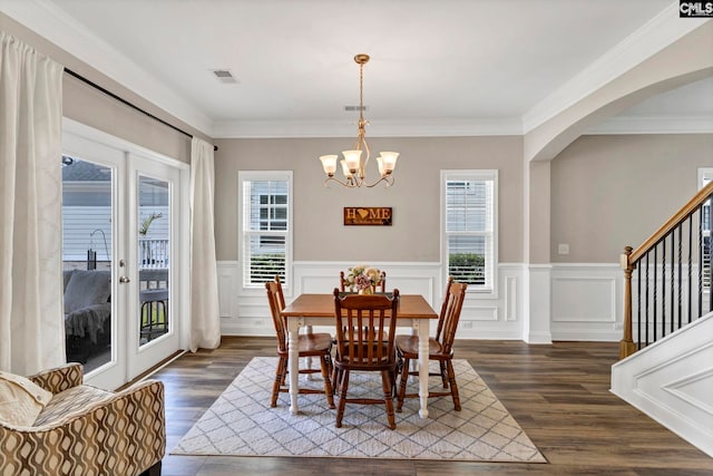 dining area with arched walkways, a notable chandelier, dark wood-style flooring, stairs, and ornamental molding